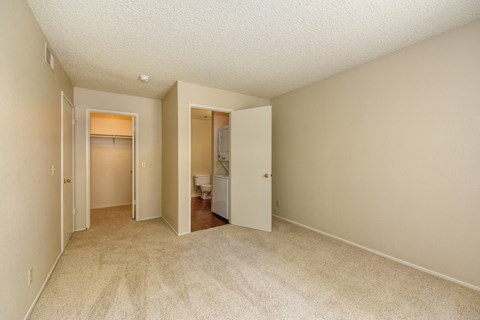 Empty Bedroom with Carpet, Open Bathroom Door, and Closet